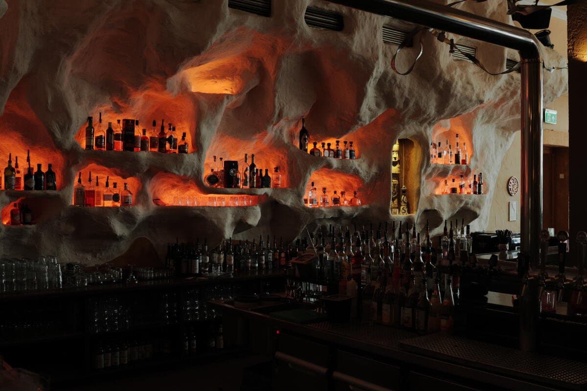 Warm beleuchtete Bar-Regale mit Spirituosen bei Dos Amigos